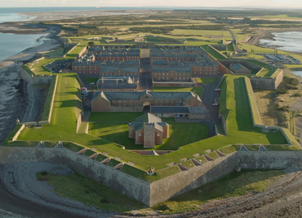 An aerial view of Fort George in in Inverness by the coast with numerous buildings and walls surrounding them and raised grass