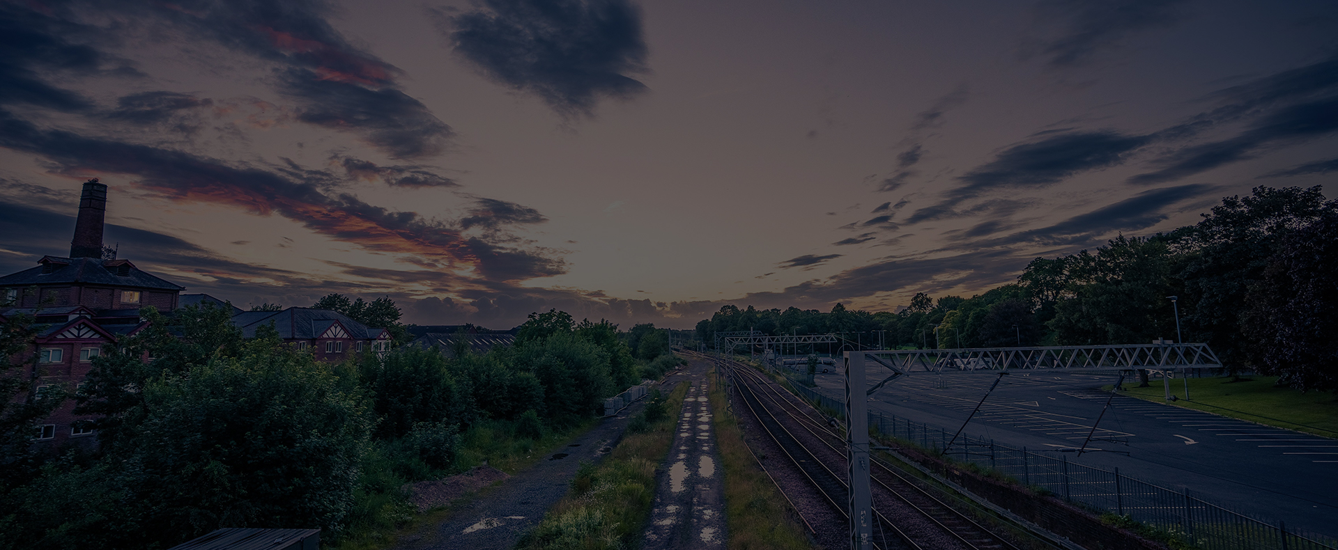 trainline carlisle next to gravel grass and trees with old buildings in the town to the side