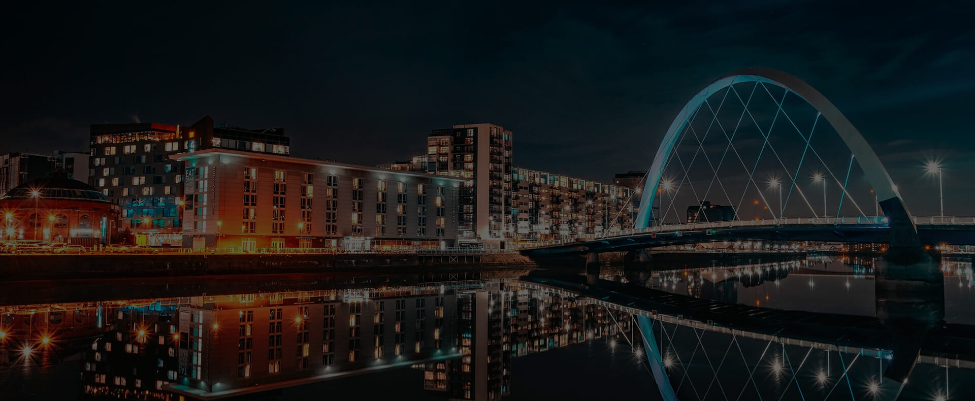 glasgow city arc bridge over river clyde at night with lit buildings to the side
