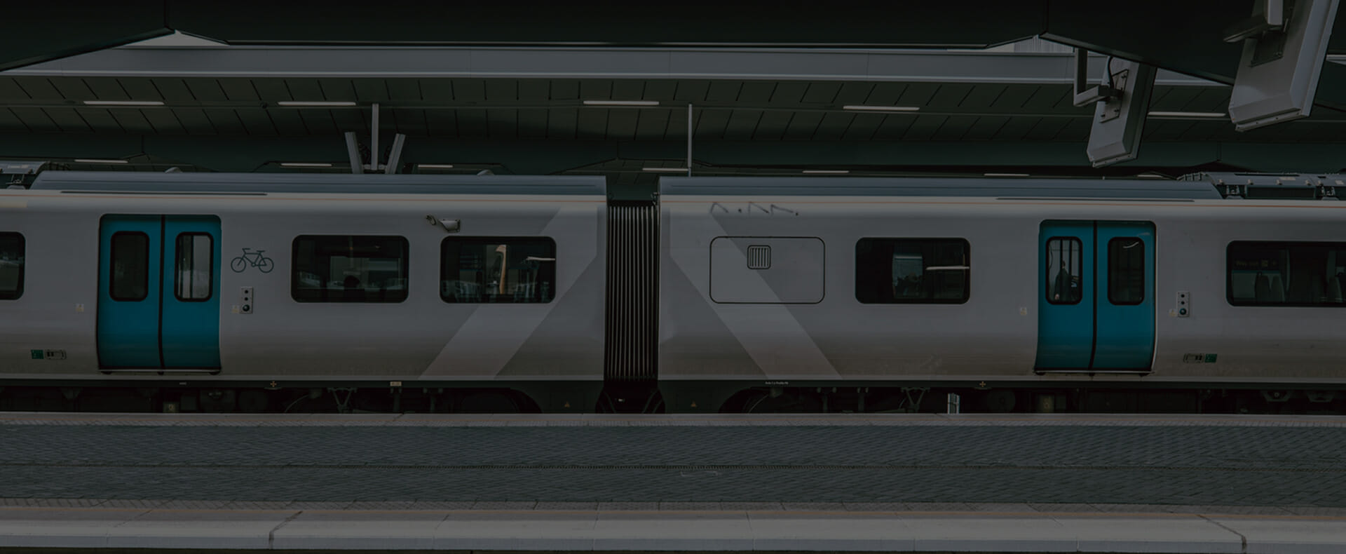 thameslink london grey train waiting at platform with carriage for bicycles and departure boards alongside