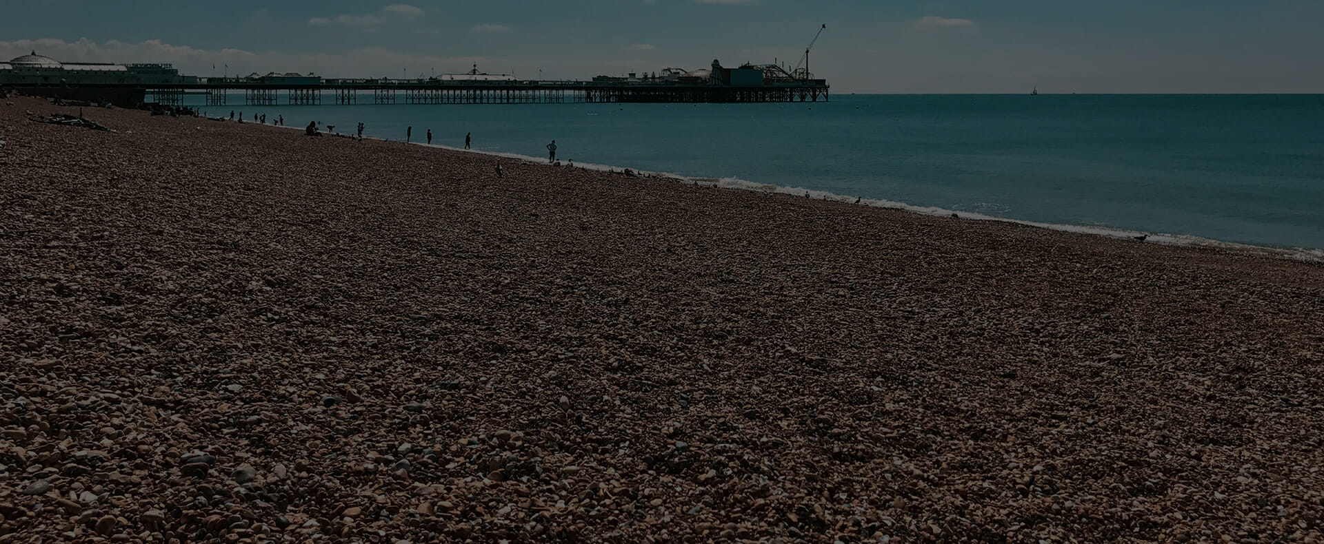 people standing in sea by brighton beach with brighton pier in distance