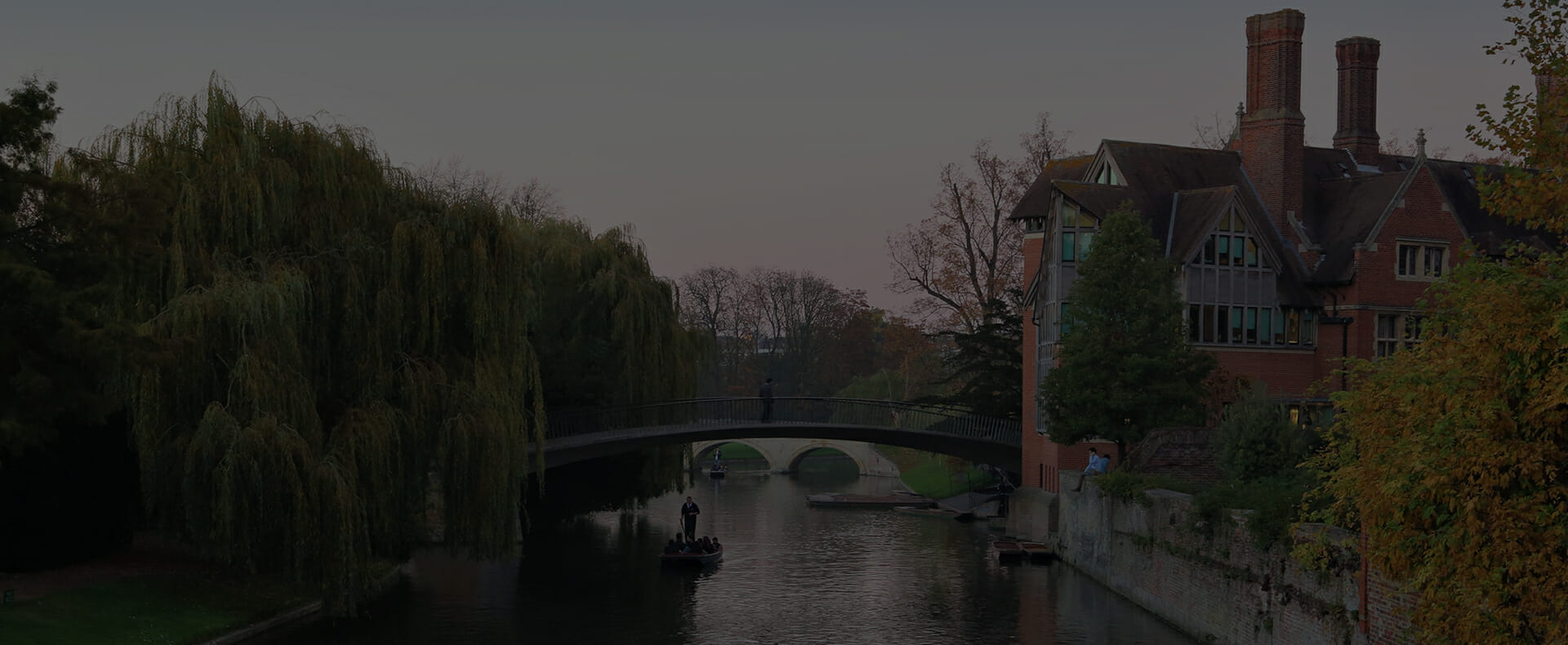 trees, a bridge, and a house over looking the river cam in cambridge with a punt on the river
