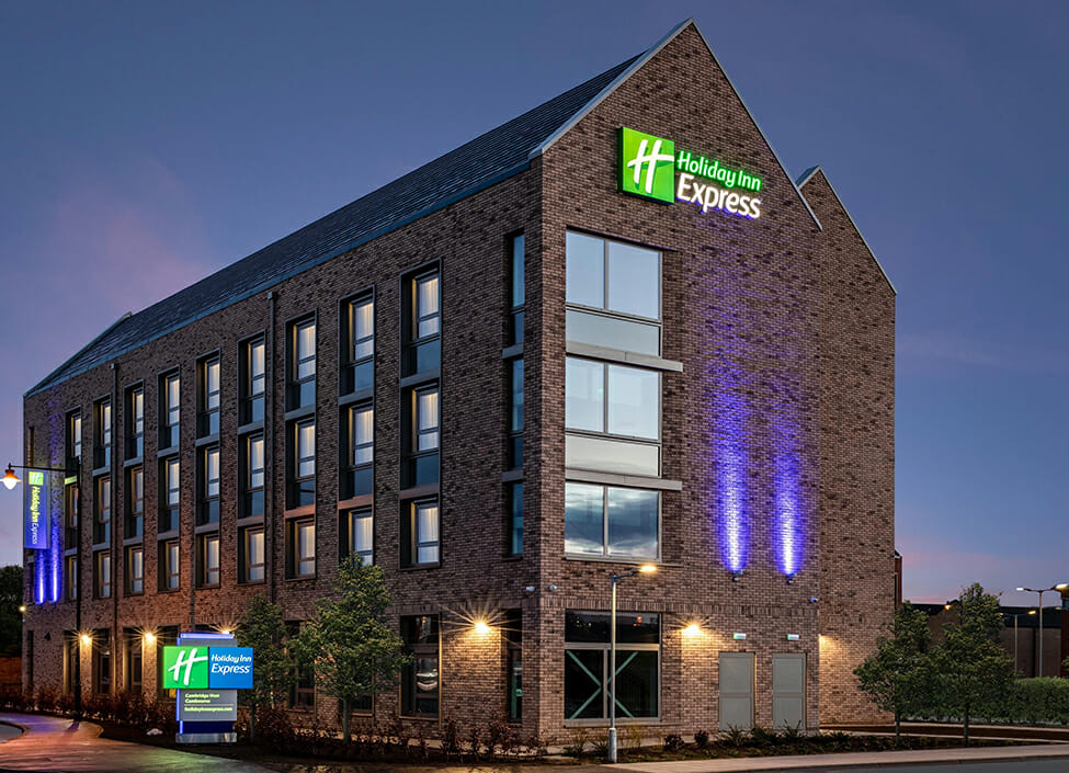 Holiday Inn Express Cambridge hotel at night with blue uplighting