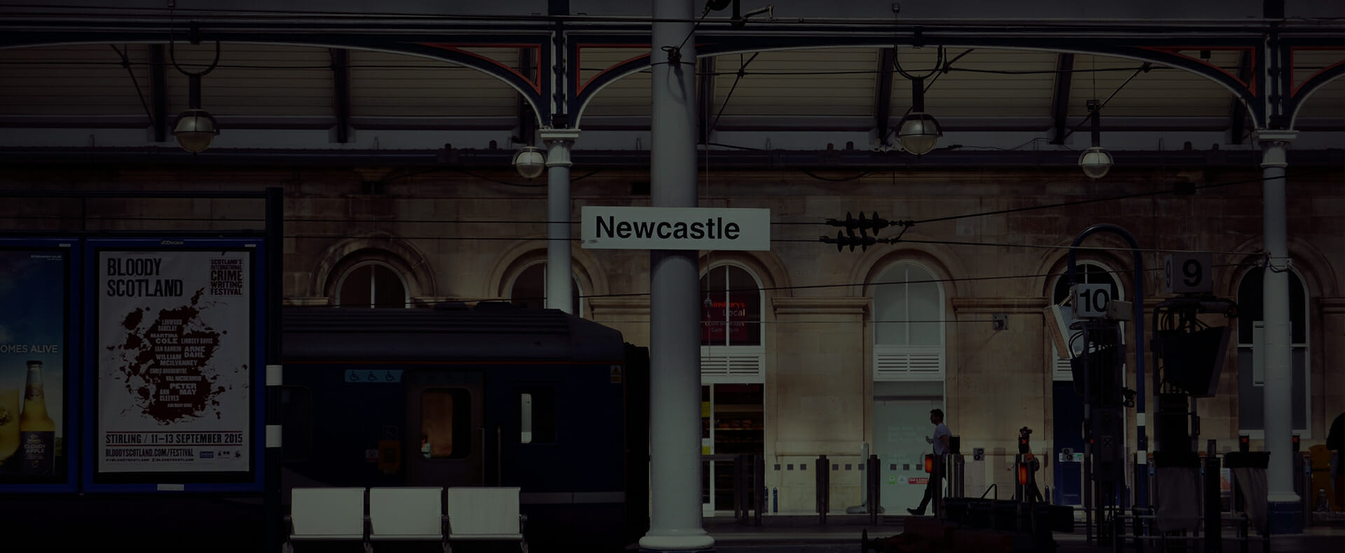 newcastle central station platform 10 with a sign and passengers walking in the background