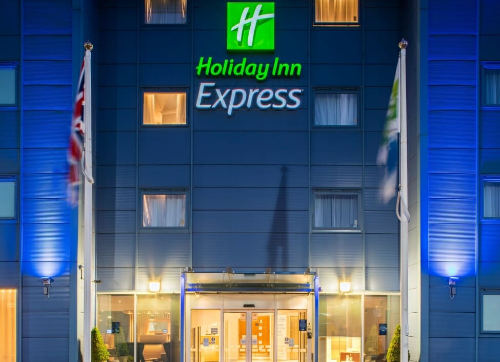  Holiday Inn Express Oxford - Kassam Stadium hotel over multiple levels with a big sign and lights on the ground floor