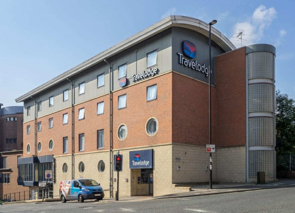 Travelodge Newcastle Central in daylight next to a quiet road with a van and traffic lights in front