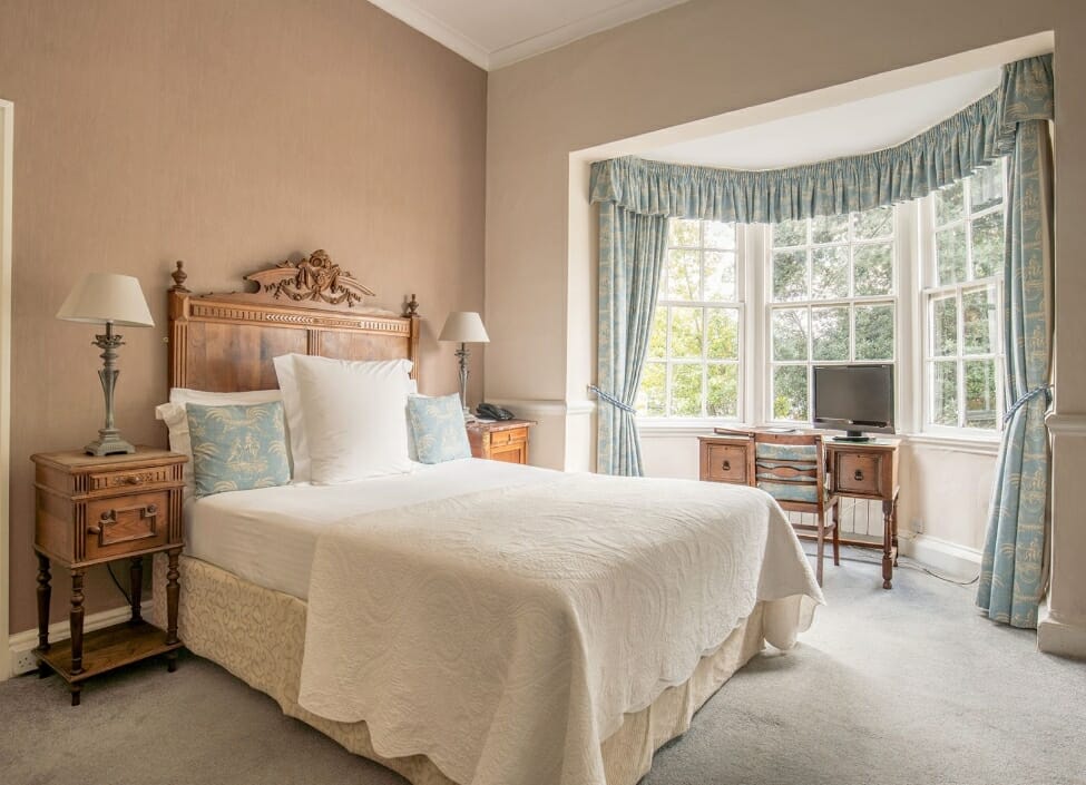 Diglis House Hotel room during the day with double bed desk and furniture with green curtains and bedding