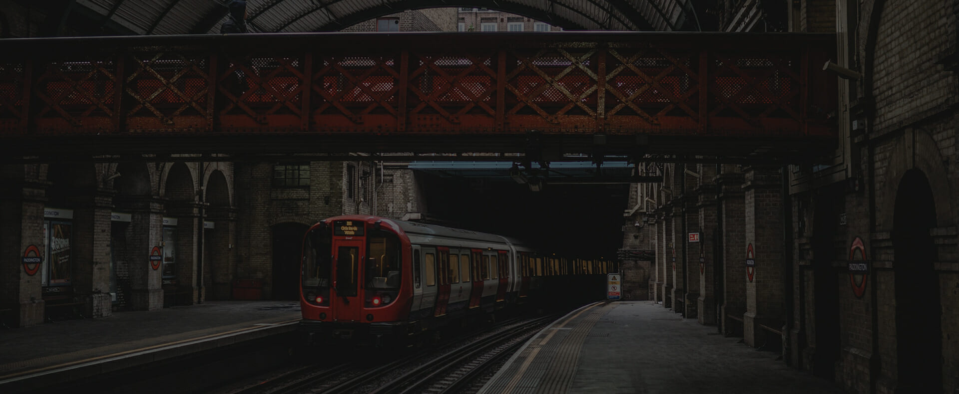 train waiting at london paddington train station platform with footbridge above