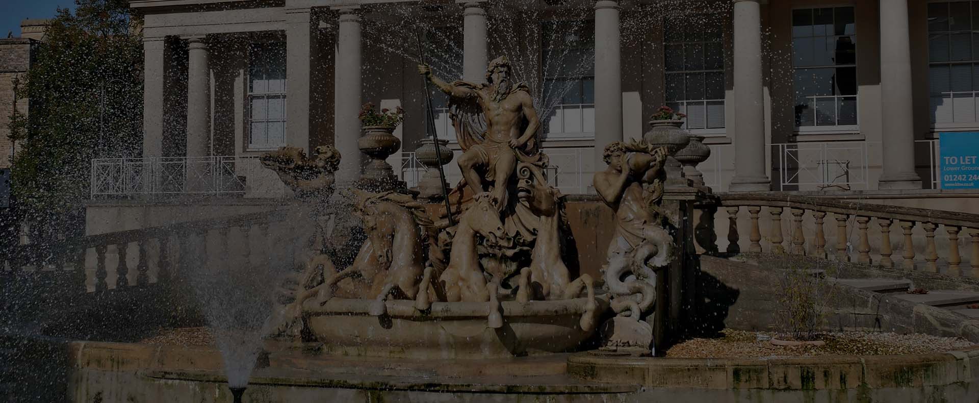 neptune fountain cheltenham with a building in background