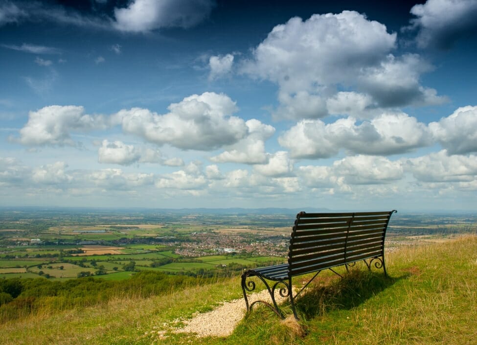 cleeve hill cheltenham with a bench and fields and cloudy sky