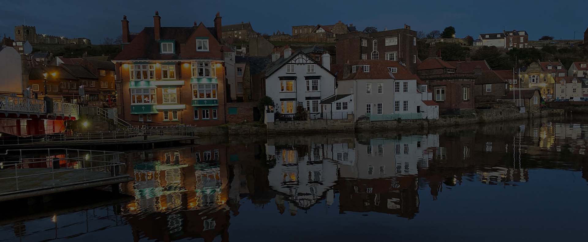 houses by the river esk in whitby at night with a bridge to the left