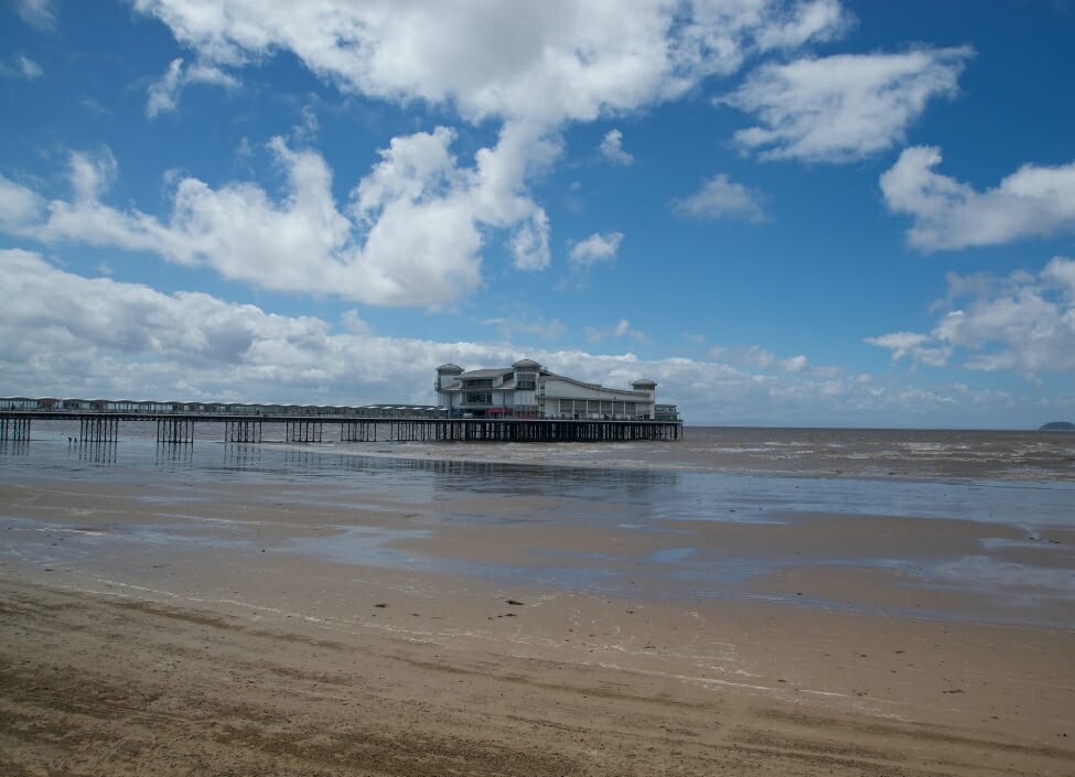 weston super mare grand pier with beach in front and blue cloudy sky
