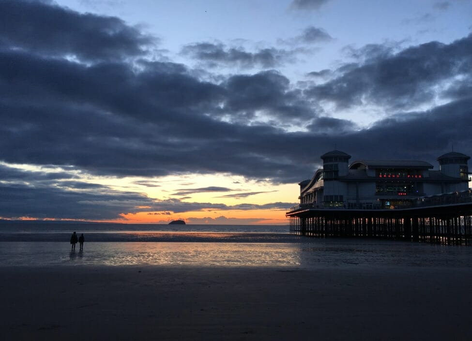 weston super mare sand bay at night with sunset and people walking on beach