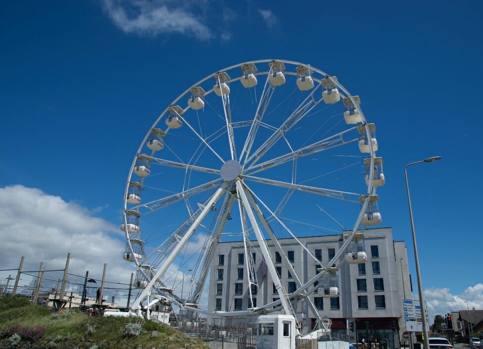 weston super mare wheel with grey building and blue cloudy sky in background