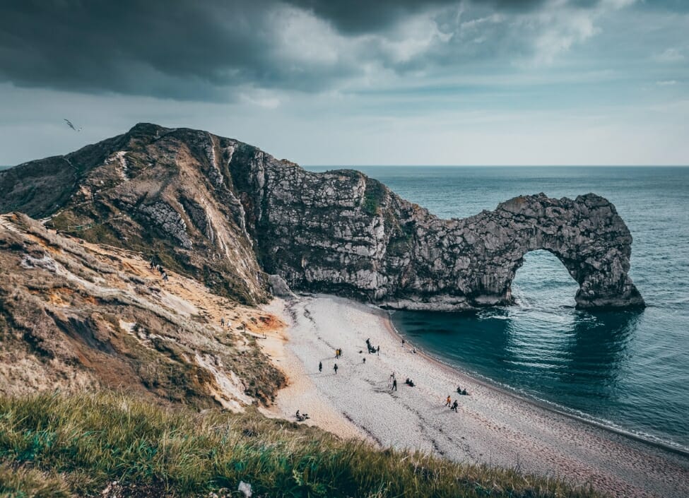 weymouth durdle door arch by the beach with sloped grass next to the sea