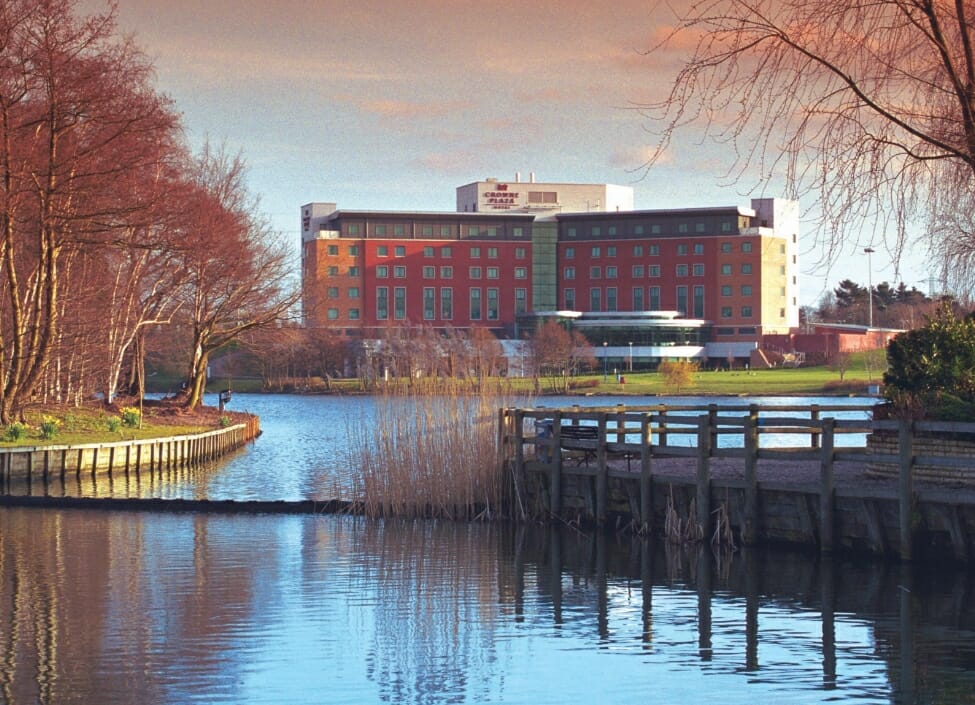 a view of crowne plaza birmingham NEC from across the Pendigo Lake with an island to the left with trees