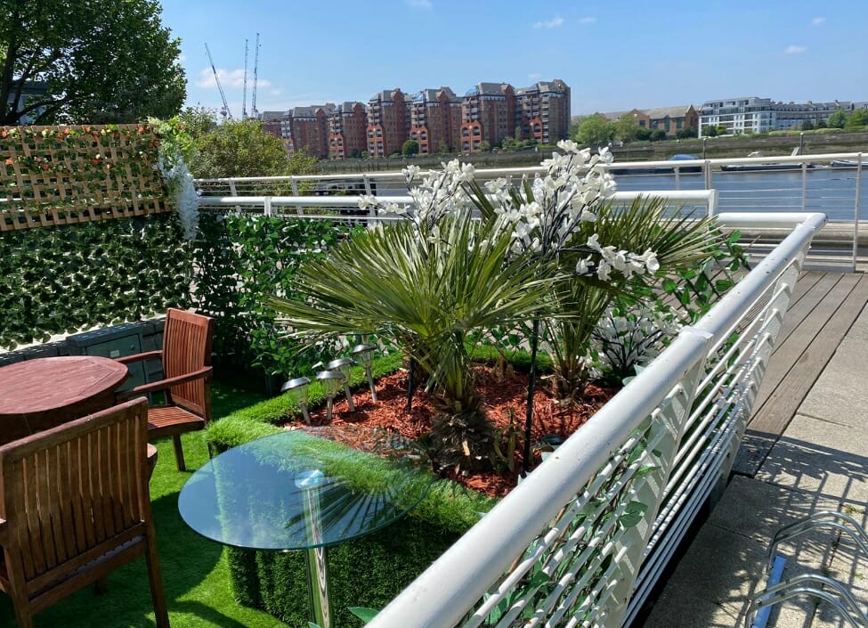 garden at hotel rafayel with table and chairs and plants, in the background the river with trees and buildings on the other side