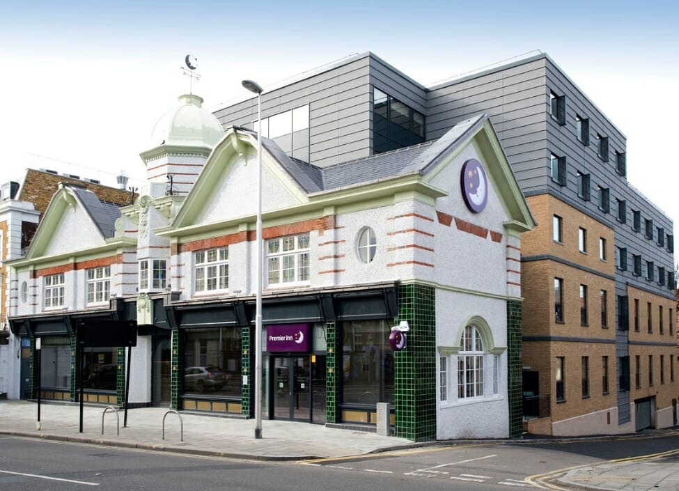 premier inn london clapham hotel building exterior, white front with bricks and cladding behind, to the front, a pavement and road