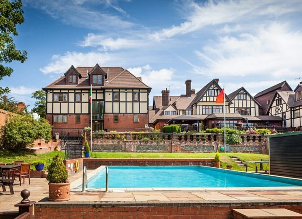De Rougemont Manor tudor style buildings with a swimming pool, patio and grass in front
