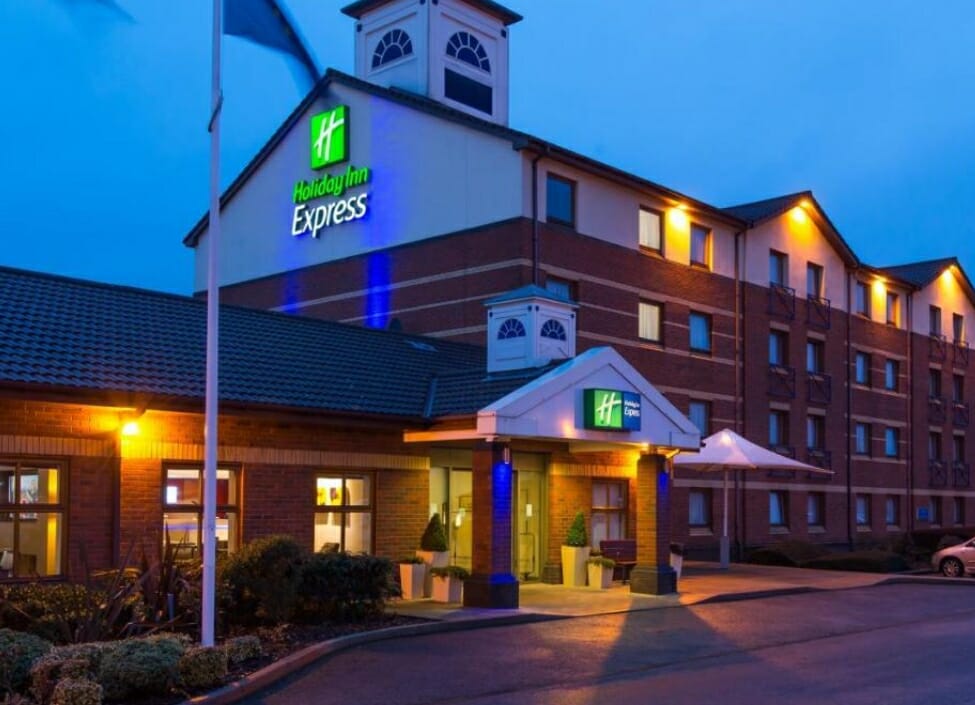 Holiday Inn Express Derby Pride Park by the road at night with a car park in front of the hotel