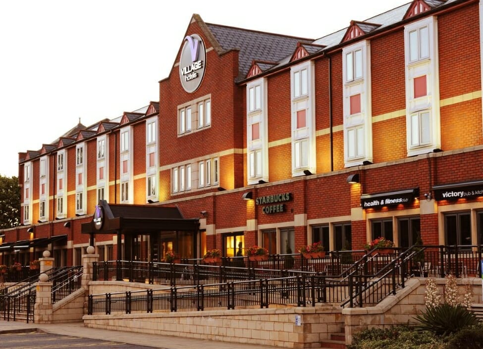 Village Hotel Coventry lit up at night with numerous windows and steps to the front