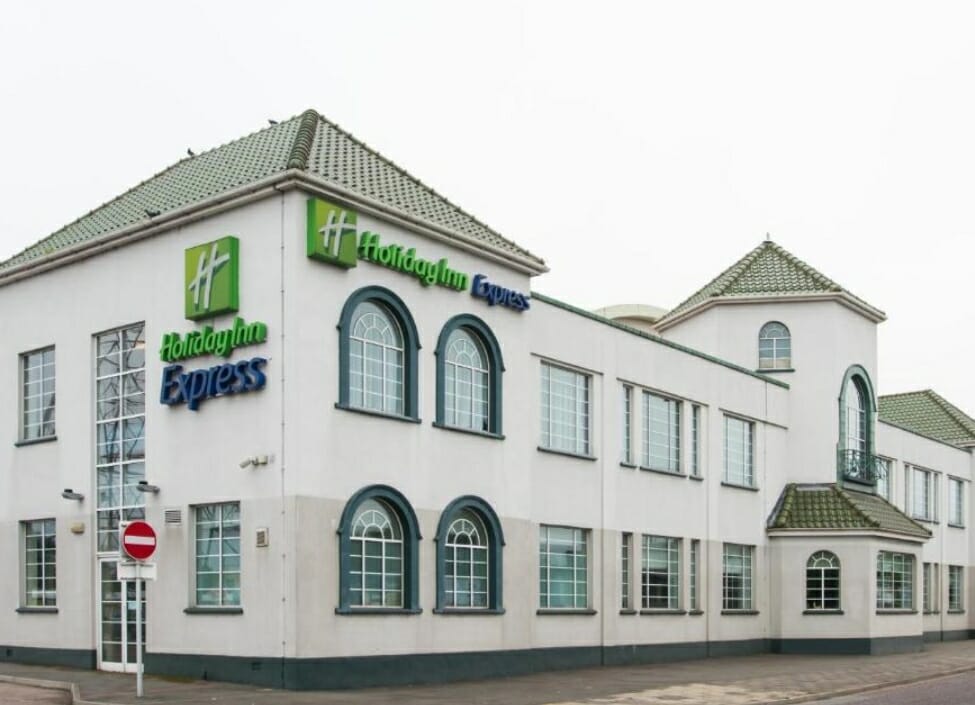 Holiday Inn Express London Chingford Hotel, a white building with large windows next to a quiet road
