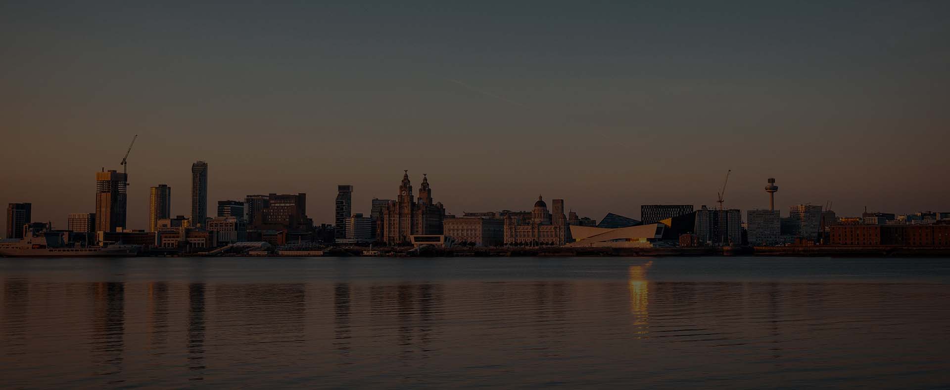 Albert Dock in Liverpool City Centre with buildings on land and the River Mersey in front.