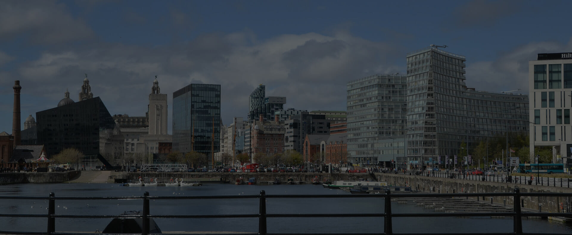 royal albert dock in liverpool with a view of several tall buildings and a cloudy sky in the background