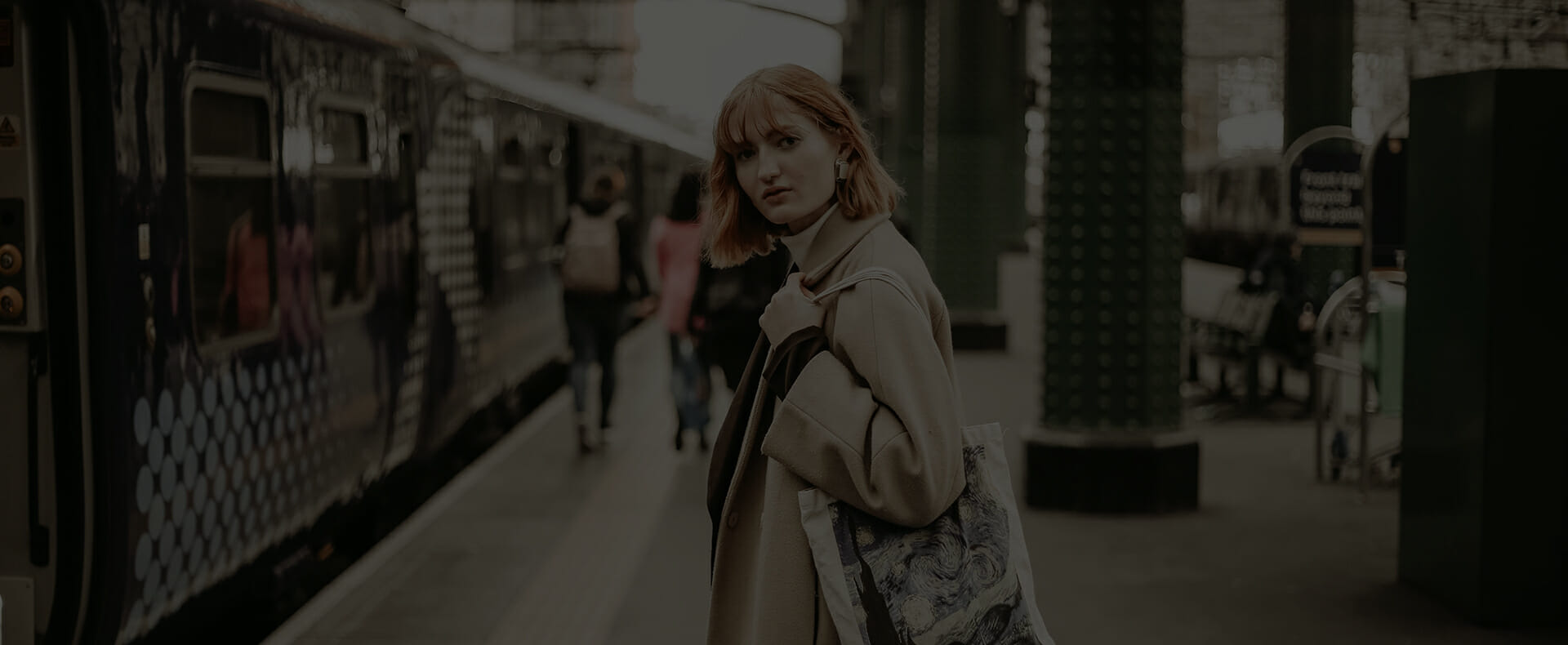 passenger looking at camera waiting on platform next to train at glasgow station