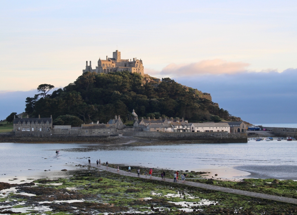St Michaels Mount, a crossing with the tide in to an island surrounded by sea with buildings at the bottom and a castle at the top