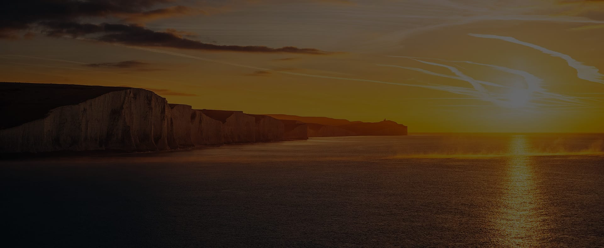 a sunset at seven sisters cliffs in eastbourne with the sea in the foreground
