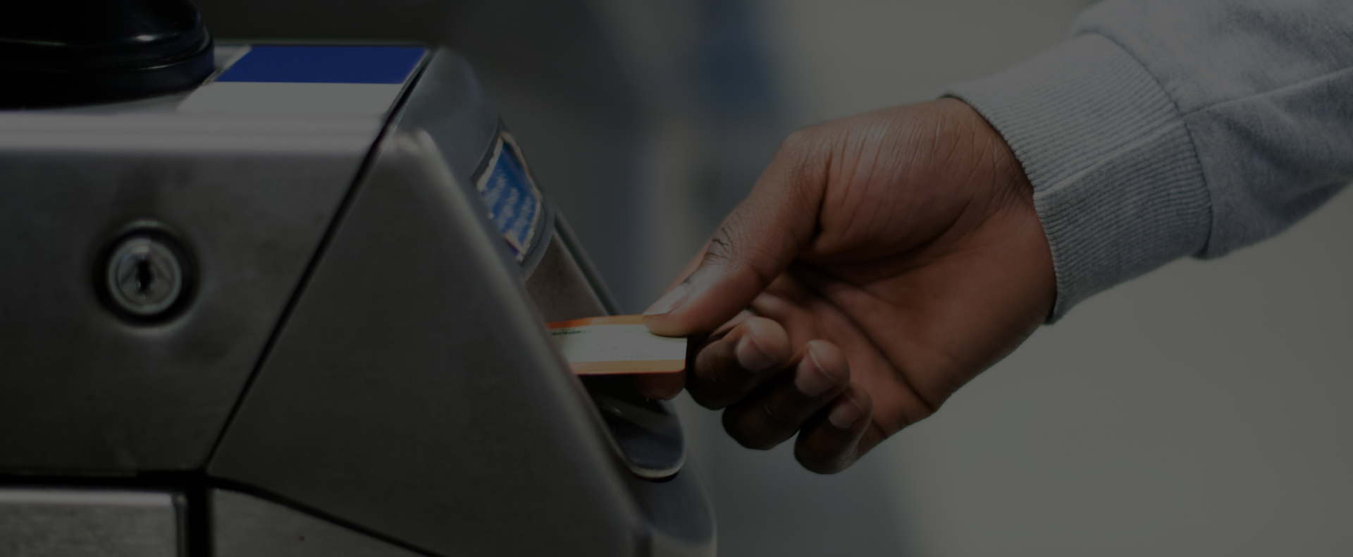 A passenger at at train station in the UK inserting a train ticket into a ticket gate for validation.