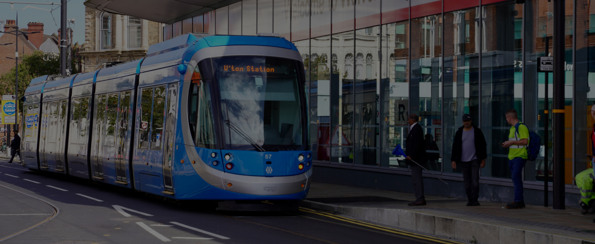 A tram stopped at Wolverhamtpon Station with passengers waiting to board.