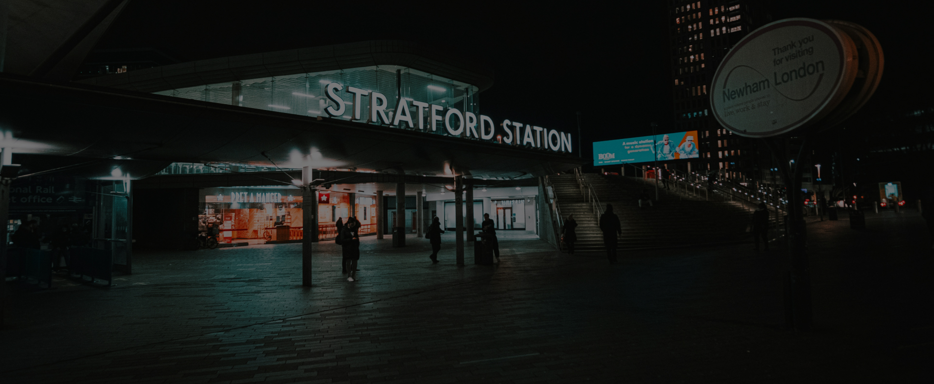 Stratford Train Station in london with a big sign and paving outsides with passengers walking.